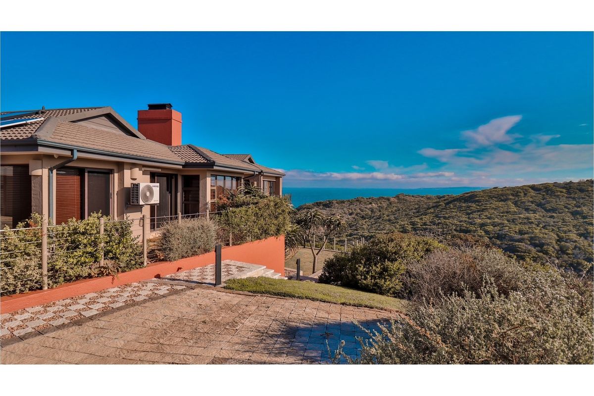 Exterior view of the property featuring a paved patio area, landscaped garden, and scenic coastal views.
