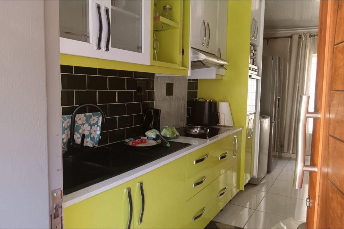 Modern kitchen featuring vibrant lime green cabinetry, black subway tile backsplash, stone countertops, and integrated appliances including an oven and cooktop.