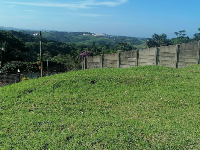 A view of the vacant residential land featuring a well-maintained grass lawn and a precast concrete boundary wall overlooking the surrounding landscape.