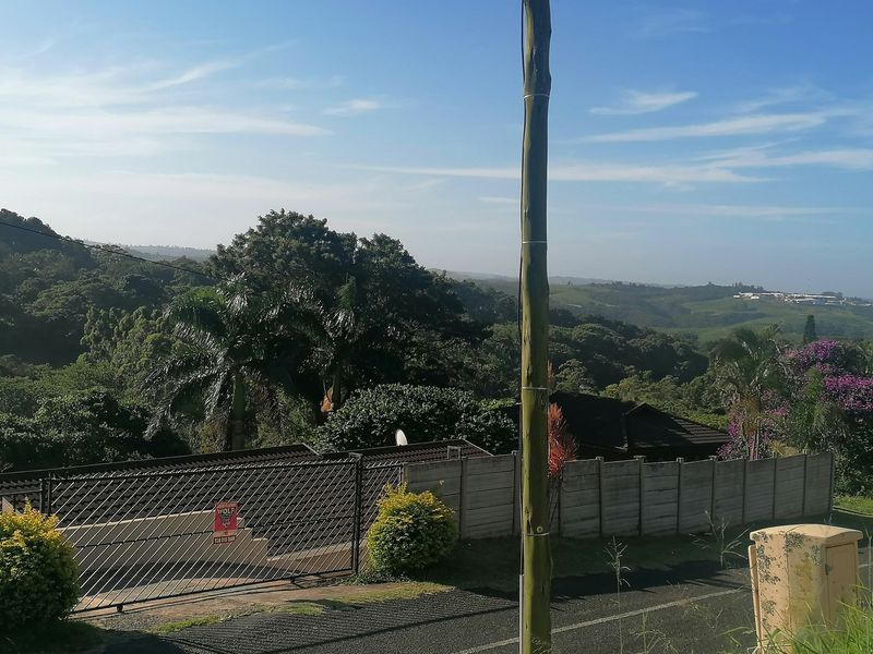 Street view of the residential property showing the entrance gate, perimeter wall, and surrounding landscape.