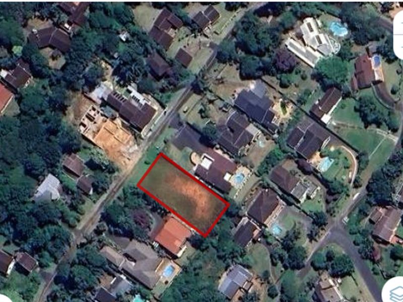 Aerial view of a vacant residential plot highlighted in red, situated within an established suburban neighborhood.