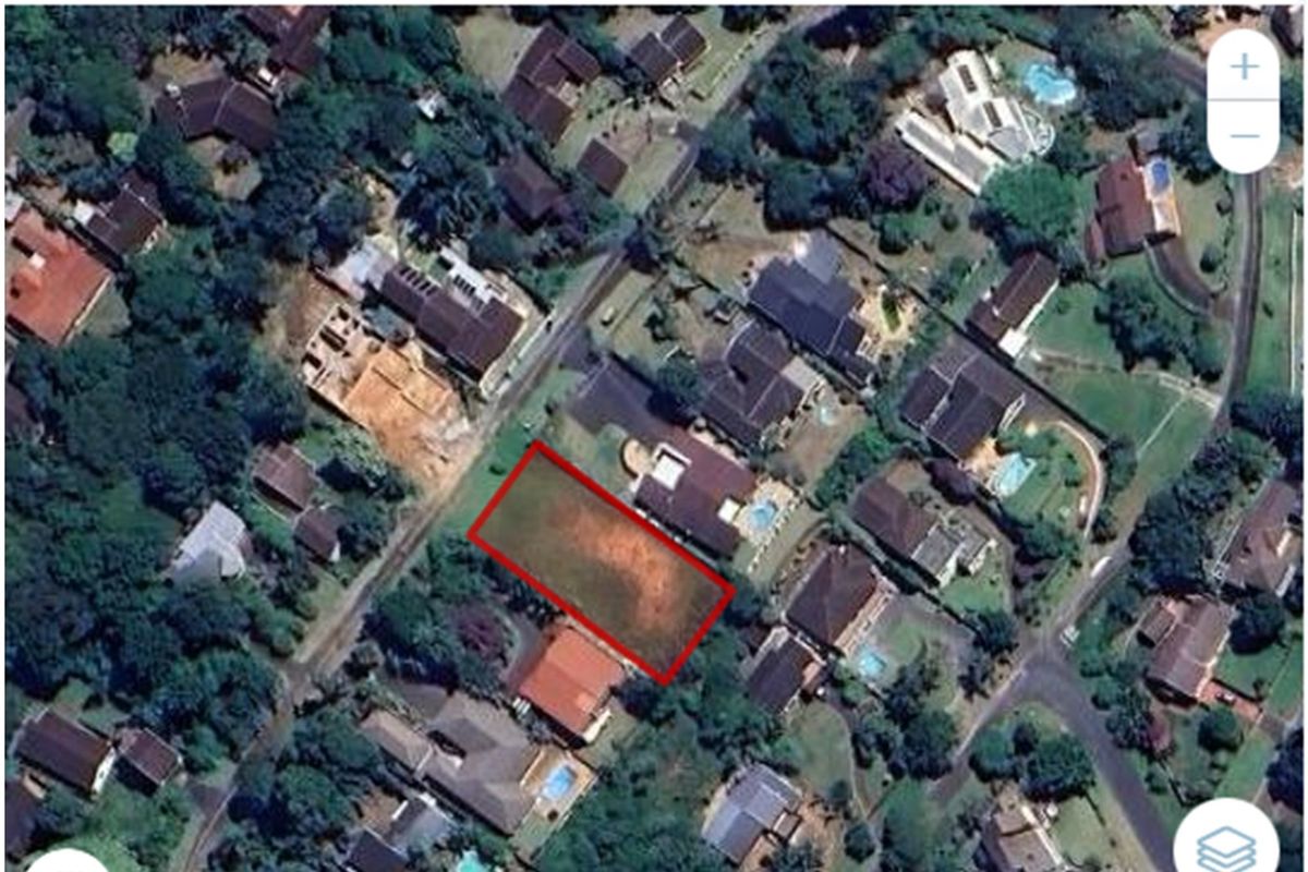 Aerial view of a vacant residential plot highlighted in red, situated within an established suburban neighborhood.