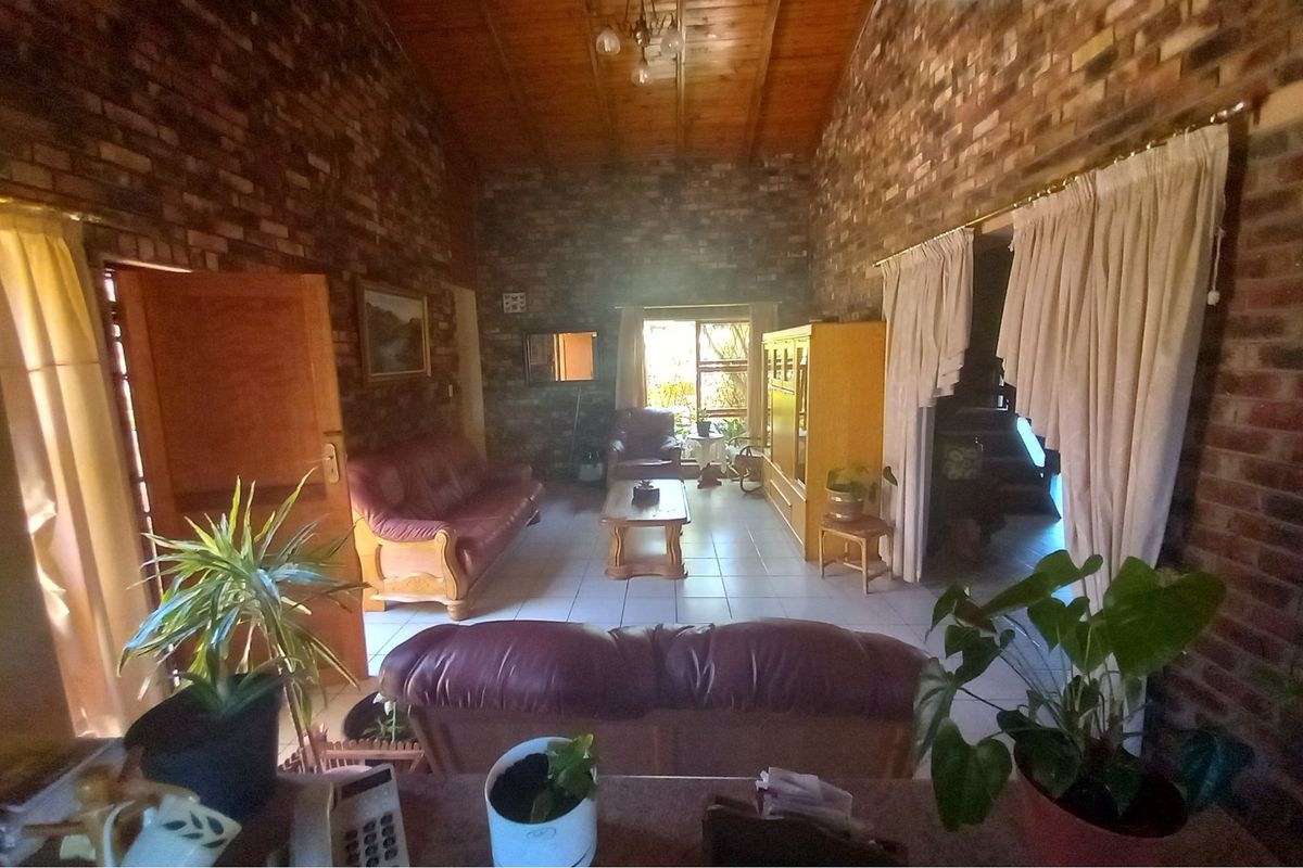 Spacious living room featuring exposed brick walls, high timber-clad vaulted ceilings, and tiled flooring, creating a rustic and warm atmosphere.