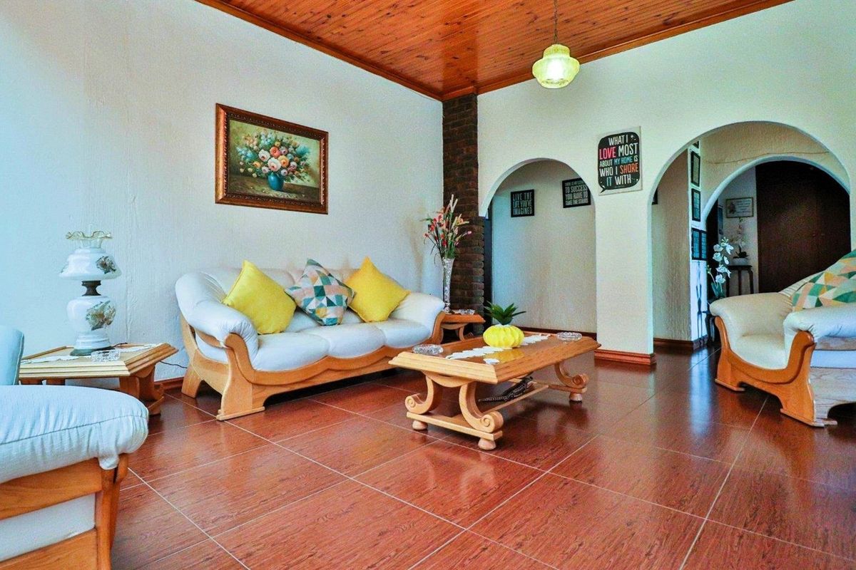A living room featuring tiled flooring, a timber-clad ceiling, and arched doorways leading to adjacent spaces.