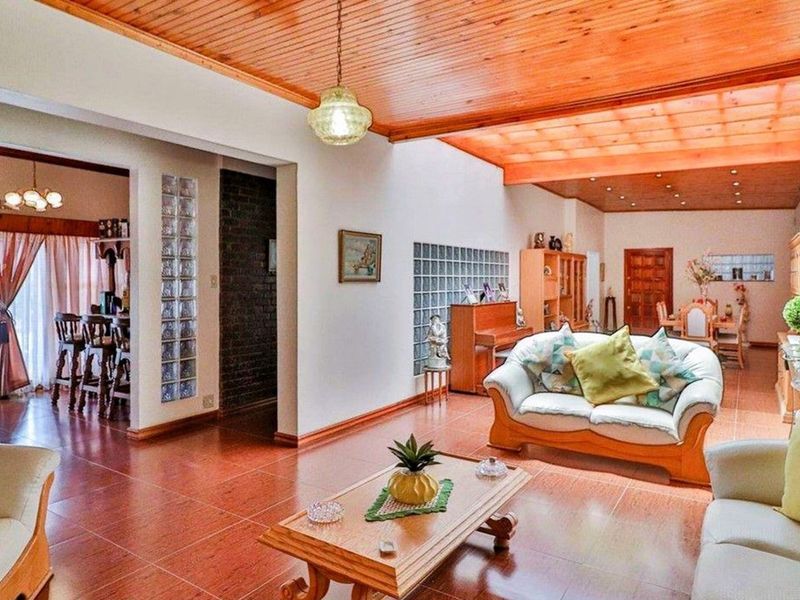 Spacious open-plan living and dining area featuring timber-paneled ceilings, glass block feature walls, and tiled flooring throughout.