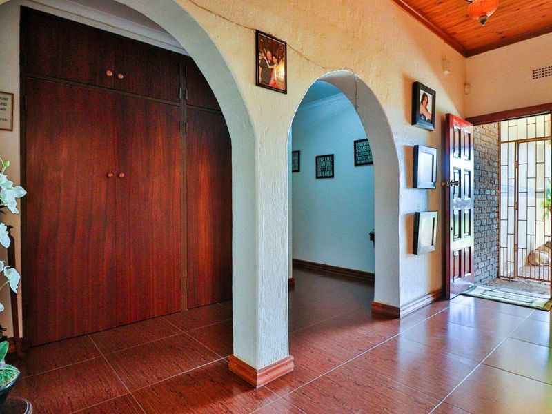 Entrance hallway featuring arched architectural details, built-in wooden cabinetry, and tiled flooring leading to an internal door.