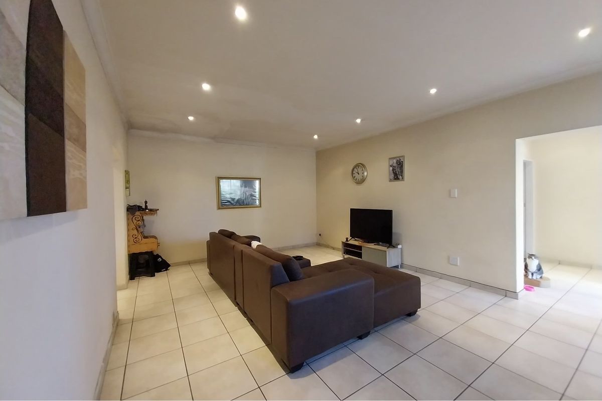 A living room featuring ceramic floor tiles and recessed downlighting, showing visible signs of water staining on the ceiling.