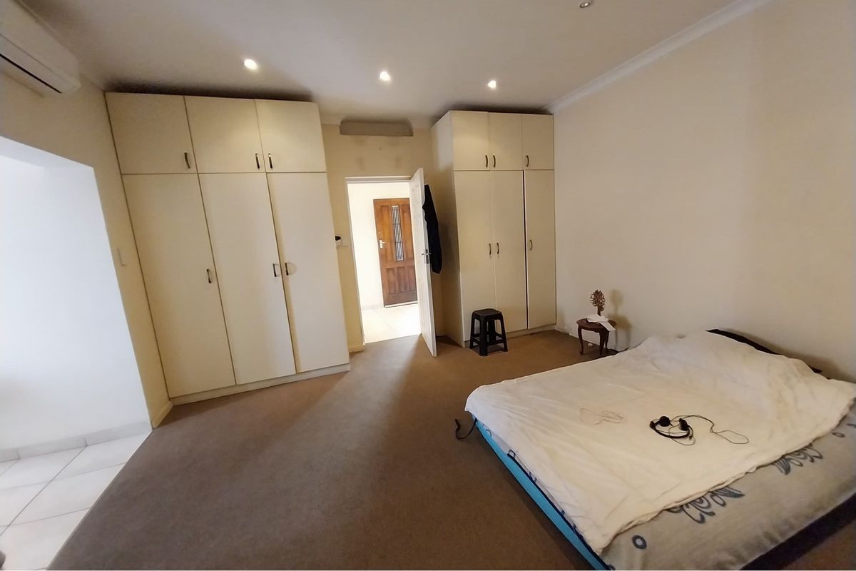 Spacious bedroom featuring extensive built-in cupboard storage, carpeted flooring, and an integrated air conditioning unit.