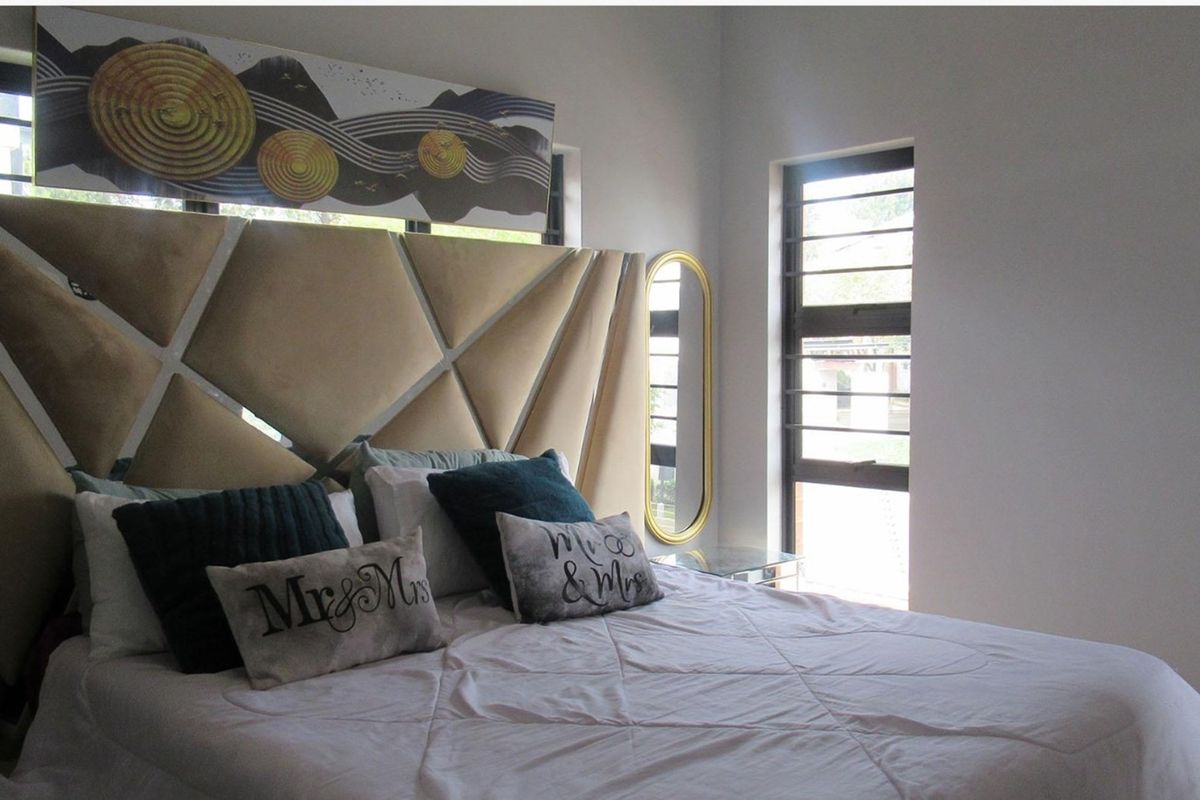 A well-lit bedroom featuring modern horizontal louvered windows and neutral wall finishes, providing a comfortable and bright living space.