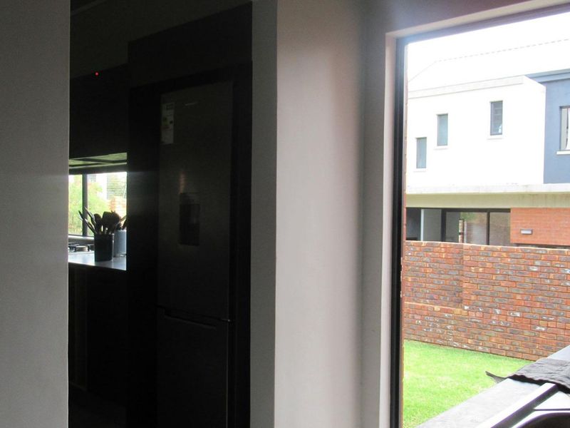 A view from a kitchen area looking out through a large window towards a neighboring property and garden.