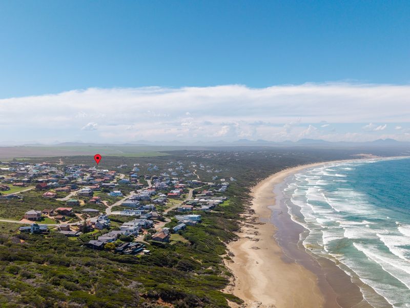 An aerial view of a coastal residential neighborhood situated along the shoreline, highlighting the property location with a map pin.