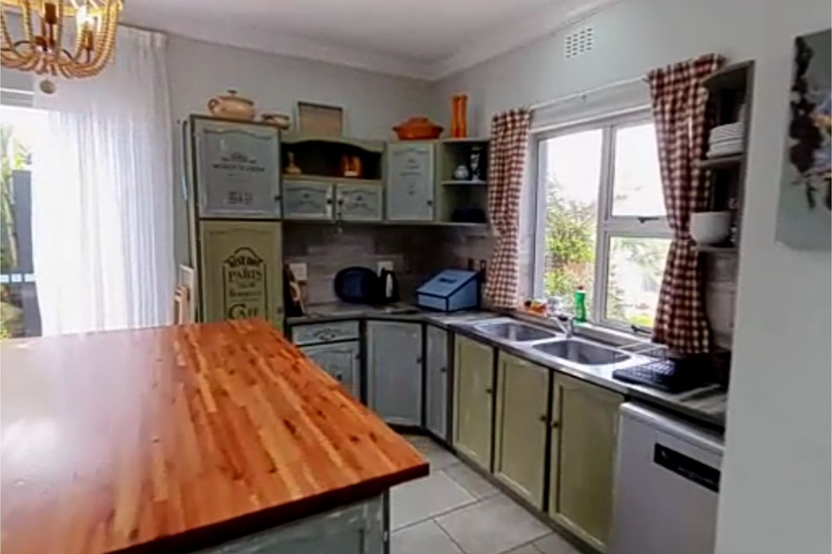 A functional kitchen featuring built-in cabinetry, a wooden countertop, and a double stainless steel sink with natural light from the window.