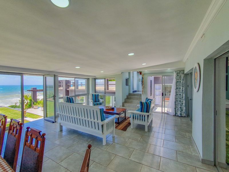 Spacious open-plan living area featuring tiled floors, recessed lighting, and large sliding glass doors that provide seamless access to the outdoor patio and ocean views.