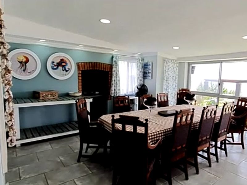 Spacious dining room featuring stone tile flooring, a brick fireplace, and large sliding glass doors providing natural light and outdoor access.