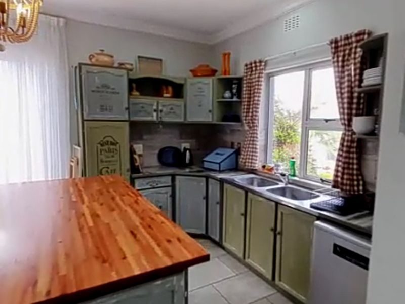 A functional kitchen featuring built-in cabinetry, a wooden countertop, and a double stainless steel sink with natural light from the window.