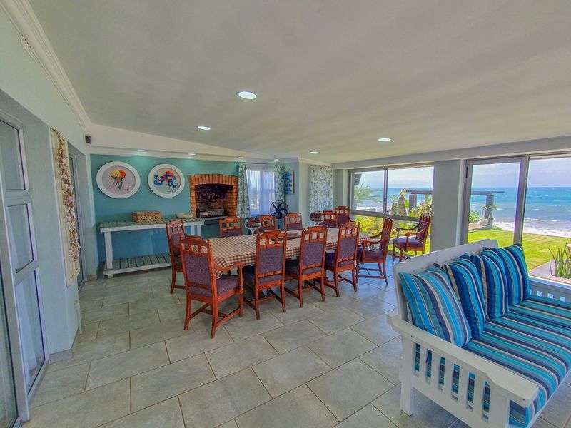 Spacious open-plan living and dining area featuring a built-in brick fireplace, tiled flooring, and large sliding doors offering panoramic ocean views.