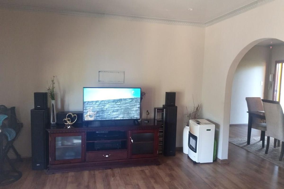 A living room featuring laminate flooring and a distinctive arched doorway leading to an adjacent dining area.