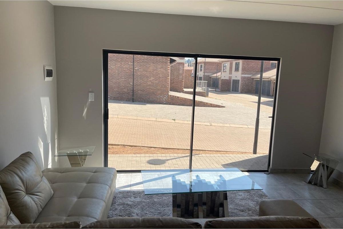 A bright living area featuring large sliding glass doors that provide direct access to the paved exterior courtyard.
