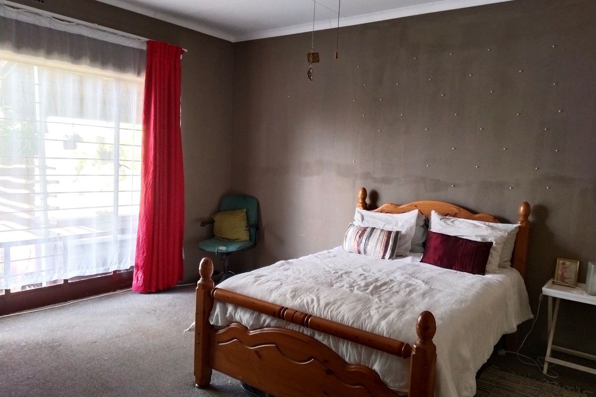 A bedroom featuring carpeted flooring, a large window with natural light, and a neutral wall finish.
