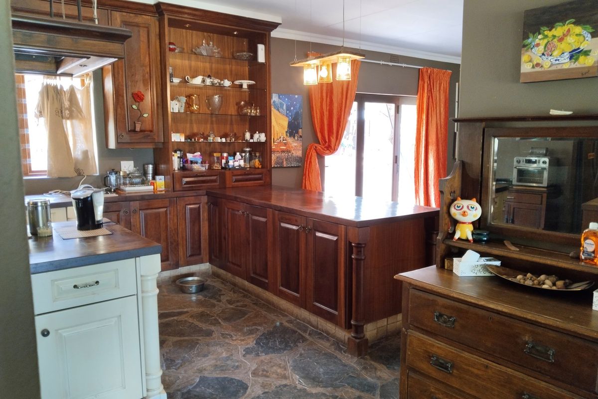 A rustic kitchen featuring dark wood cabinetry, a central island, and natural stone flooring, creating a warm and traditional atmosphere.