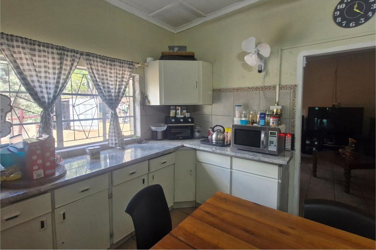 A dated kitchen featuring built-in cabinetry, laminate countertops, and tiled splashbacks, offering a functional layout with potential for modernization.
