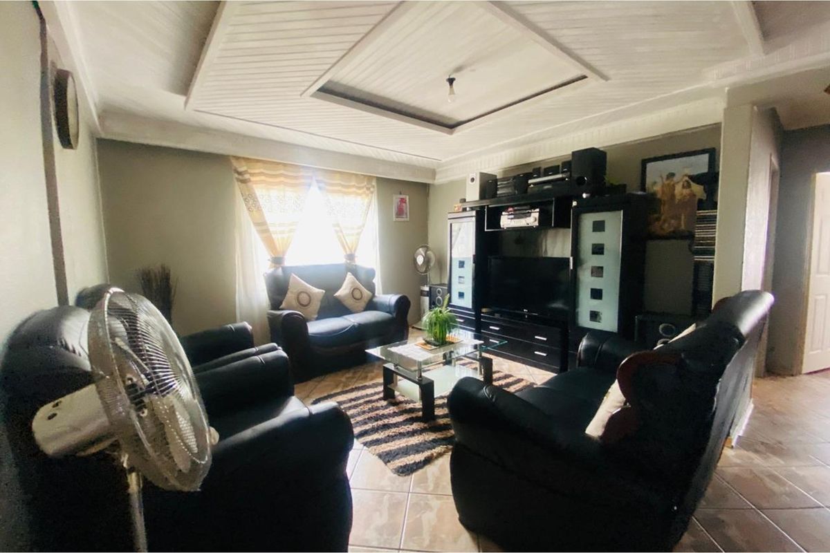 A comfortable living room featuring tiled flooring and a decorative tray ceiling, providing a functional and inviting space for relaxation.