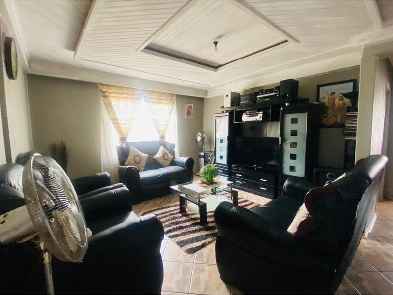 A comfortable living room featuring tiled flooring and a decorative tray ceiling, providing a functional and inviting space for relaxation.