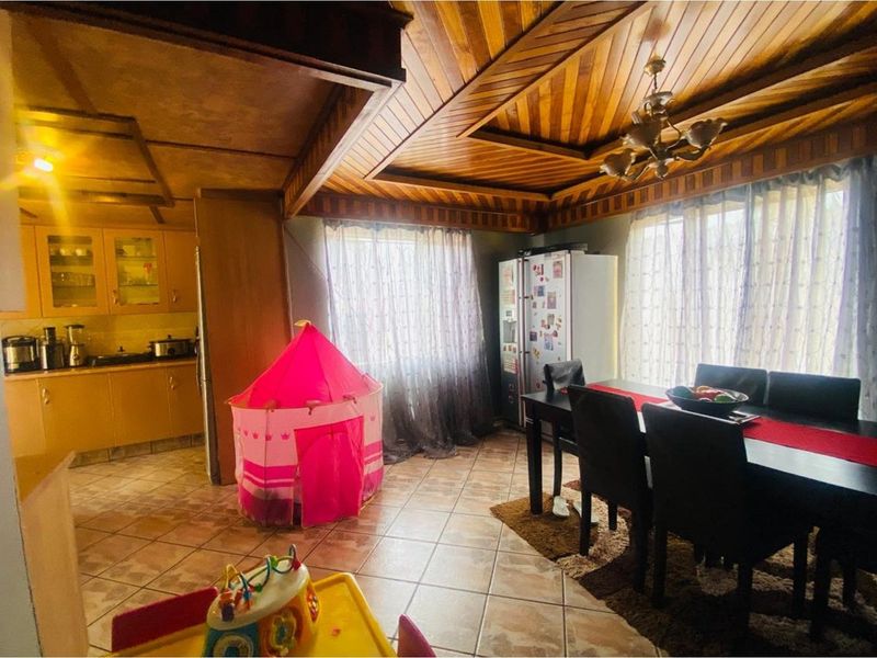 Open plan kitchen and dining area featuring wooden coffered ceilings, tiled flooring, and built-in cabinetry.