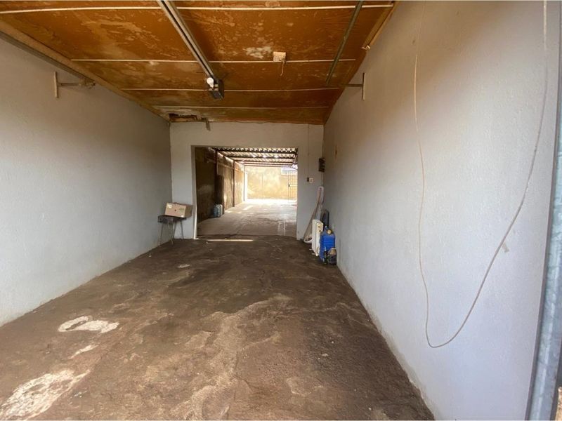 A functional garage space featuring concrete flooring and a basic ceiling structure, offering potential for storage or vehicle parking.