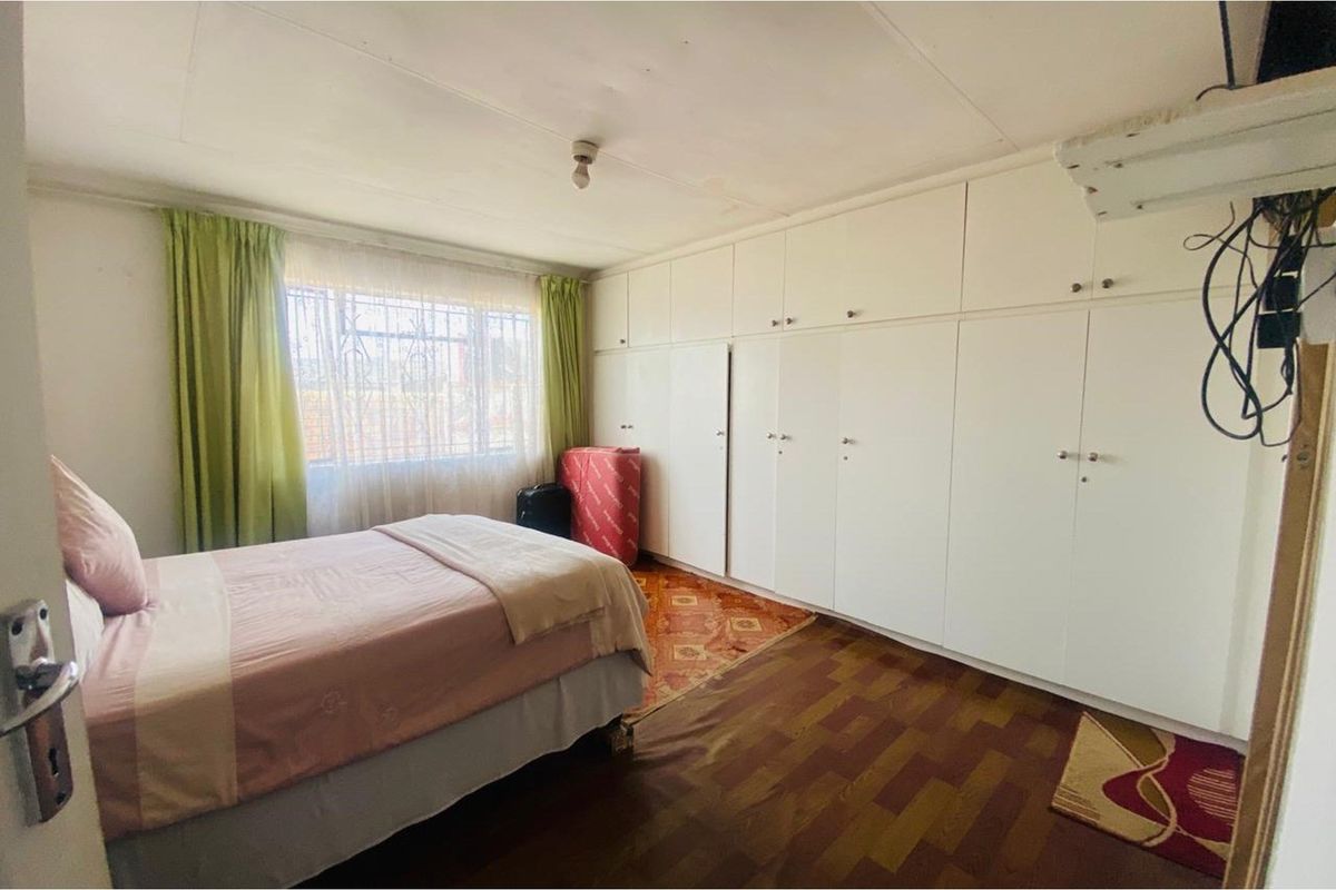 A bedroom featuring extensive built-in cabinetry, parquet-style flooring, and security bars on the window.