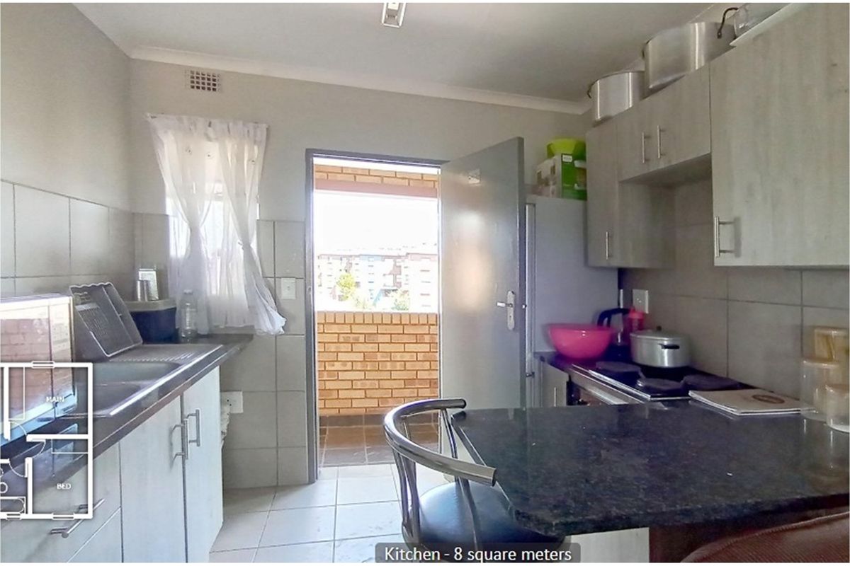 Compact kitchen featuring built-in cabinetry, stone-look countertops, integrated hob, and direct access to an outdoor balcony area.