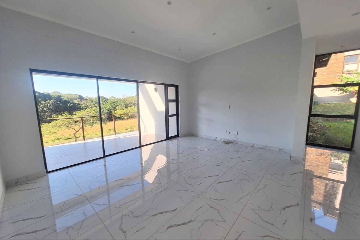 Spacious, light-filled living area featuring large sliding glass doors that open onto a balcony with scenic views and modern marble-look floor tiles.