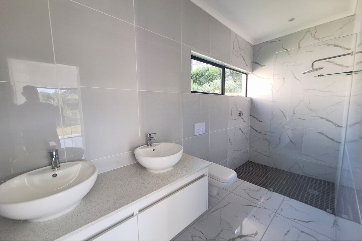 Modern bathroom featuring a double vanity with vessel sinks, a spacious walk-in shower with glass enclosure, and elegant marble-look floor and wall tiling.