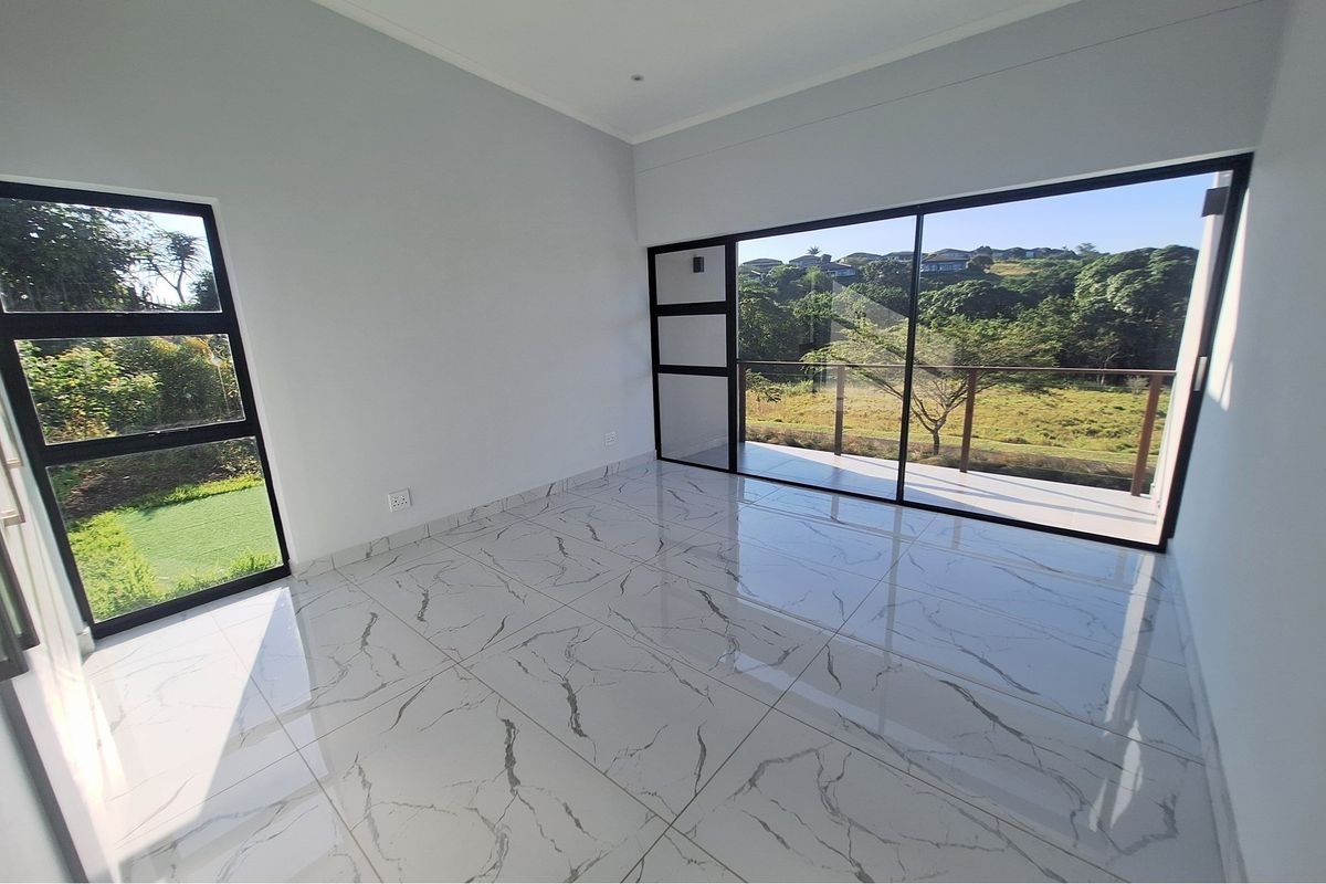 Bright bedroom featuring large glass sliding doors opening to a balcony with scenic views, complemented by modern marble-look floor tiles.