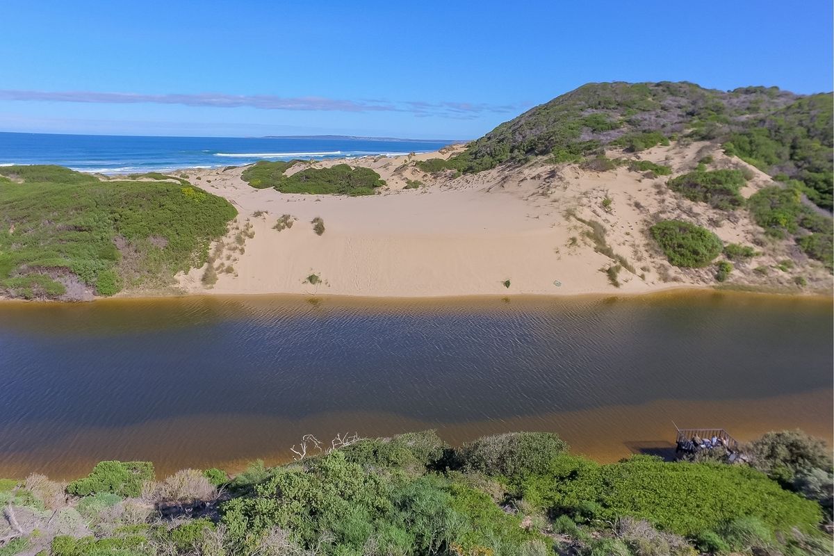 Aerial view of the vacant residential land featuring natural coastal dunes, a river, and scenic ocean views.