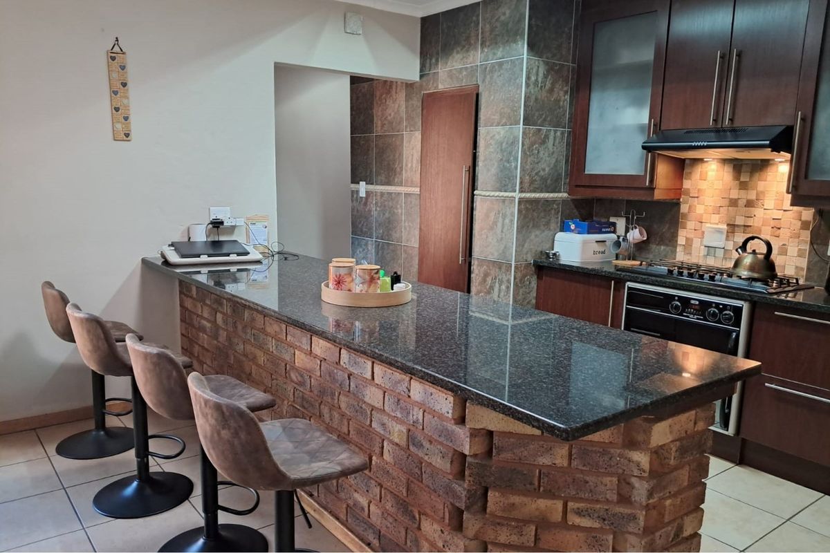 A functional kitchen featuring a granite-topped brick breakfast bar, built-in cabinetry, and integrated cooking appliances with a tiled backsplash.