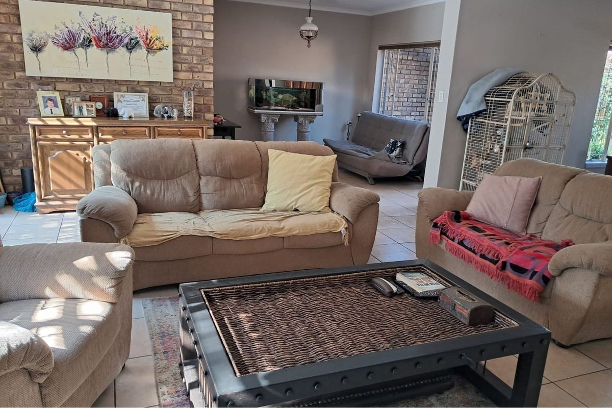 A spacious living room featuring an exposed brick fireplace and neutral tiled flooring, offering a comfortable and functional layout for family relaxation.