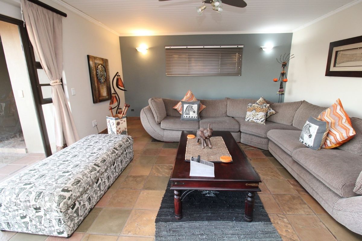 A comfortable living room featuring tiled flooring, a feature wall, and sliding glass doors providing access to the outdoor area.
