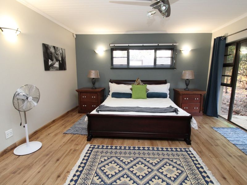 Spacious bedroom featuring wood-look flooring, a feature wall, ceiling fan, and sliding glass doors providing direct access to the outdoor area.
