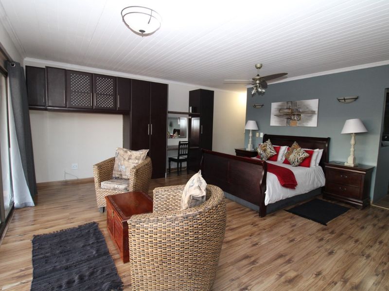 Spacious bedroom featuring built-in cabinetry, wood-look laminate flooring, a ceiling fan, and direct access to an outdoor area through sliding glass doors.