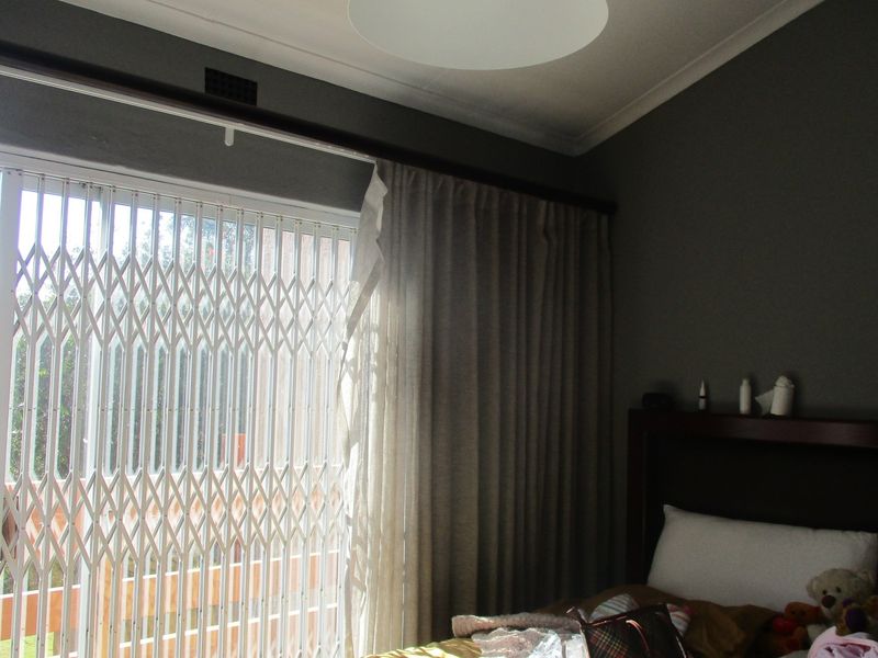 Bedroom featuring a sliding glass door with a security gate and curtain track, providing access to an outdoor area.