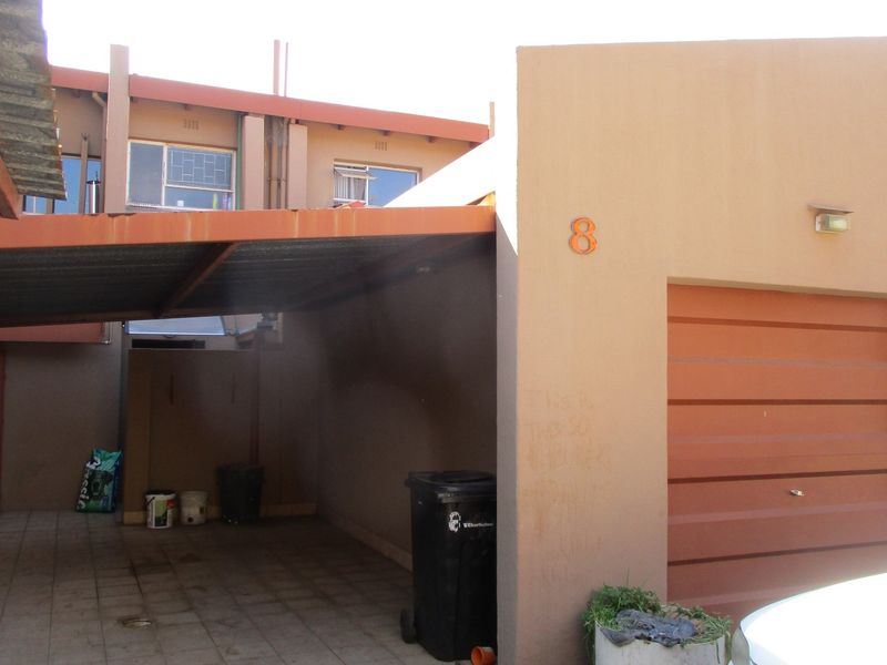 Front exterior view featuring a covered carport, a single garage door, and paved driveway area.