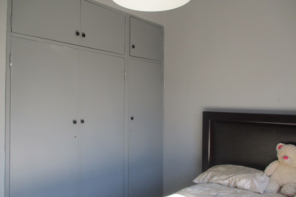 A bedroom featuring built-in floor-to-ceiling cabinetry with a neutral grey finish.