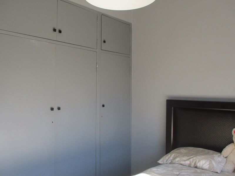 A bedroom featuring built-in floor-to-ceiling cabinetry with a neutral grey finish.