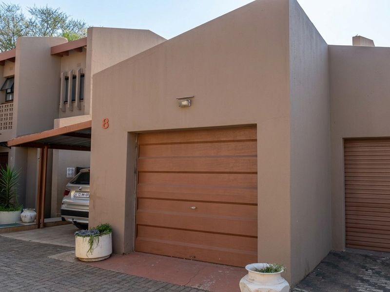 Front elevation of the property featuring a single garage door, a covered carport area, and paved driveway access.