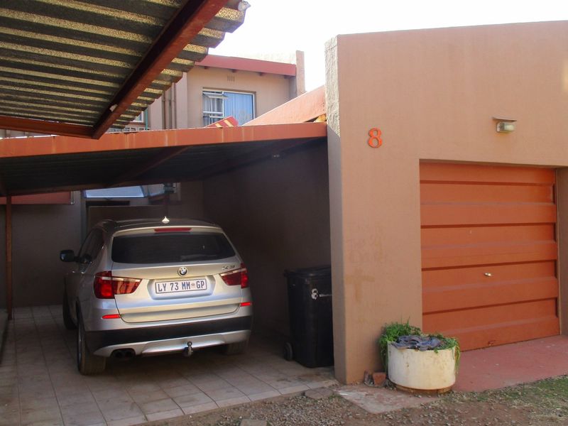 Front exterior view featuring a covered carport and an integrated single garage with a roll-up door.