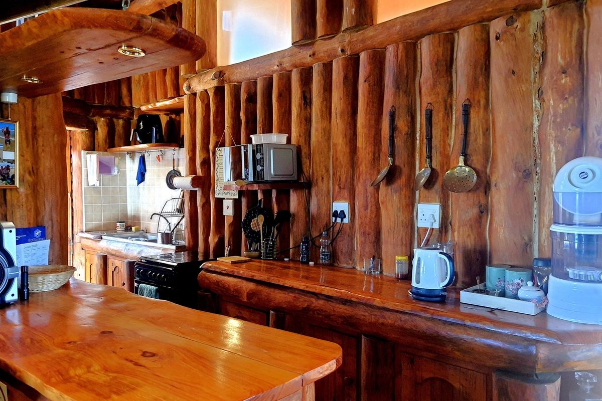 Rustic kitchen featuring extensive natural log wall cladding, custom timber countertops, and integrated cabinetry with a warm, traditional aesthetic.