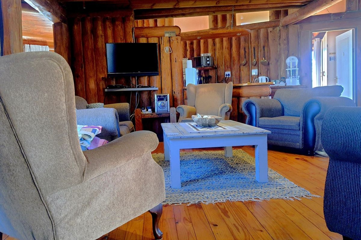 A rustic living area featuring exposed log walls and warm timber flooring, creating a cozy and traditional cabin-style atmosphere.