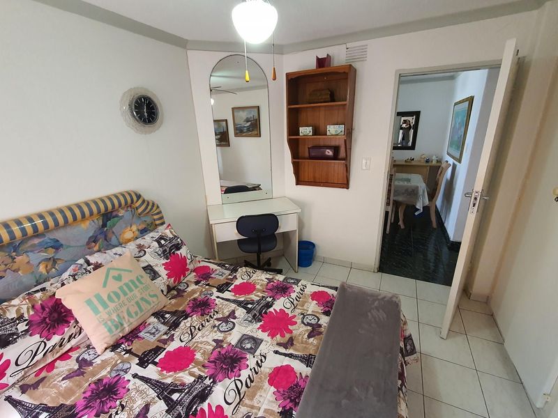 A bedroom featuring tiled flooring and a built-in vanity mirror, with direct access to an adjoining room.