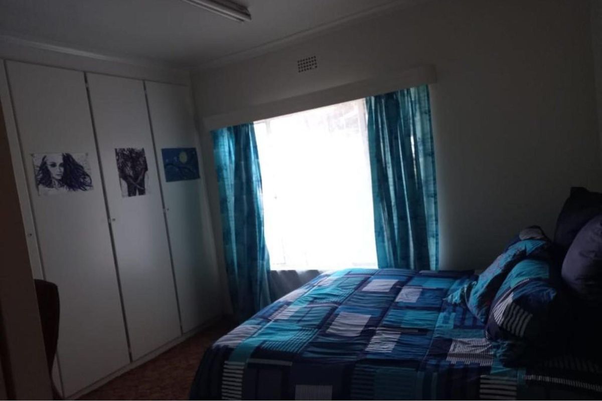 A bedroom featuring built-in cupboards and a large window providing natural light.